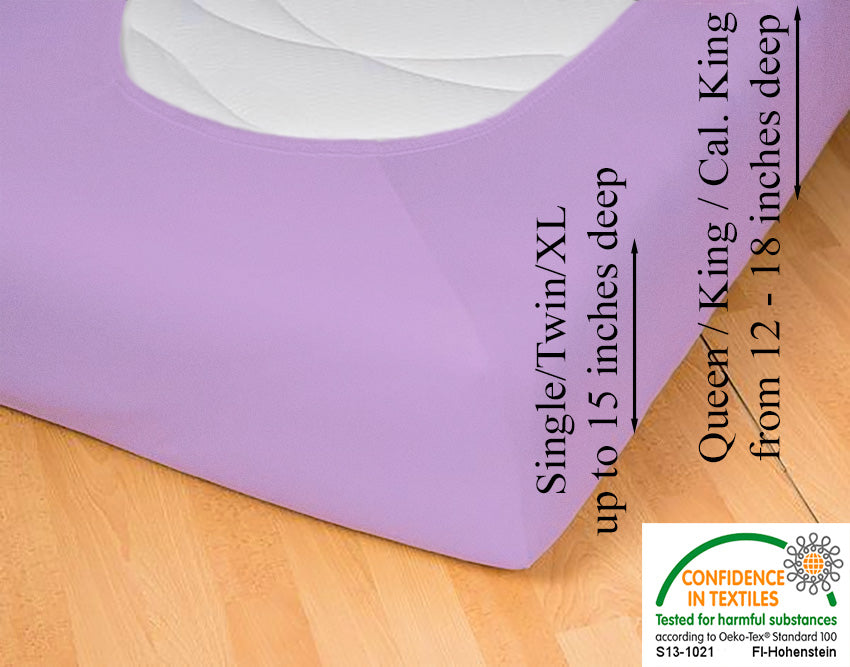 Lilac jersey-knit stretch fitted sheet on an extra-deep mattress — pulling the sidewall over a foot outward to demonstrate the abundant stretch, making sheet changing effortless even for those with limited strength or mobility.