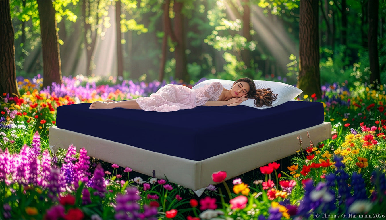 Fitted Jersey Knit stretch sheets in dark-navy with a woman relaxing on the mattress in a European wellness recreational park area, surrounded by vibrant spring wildflowers.