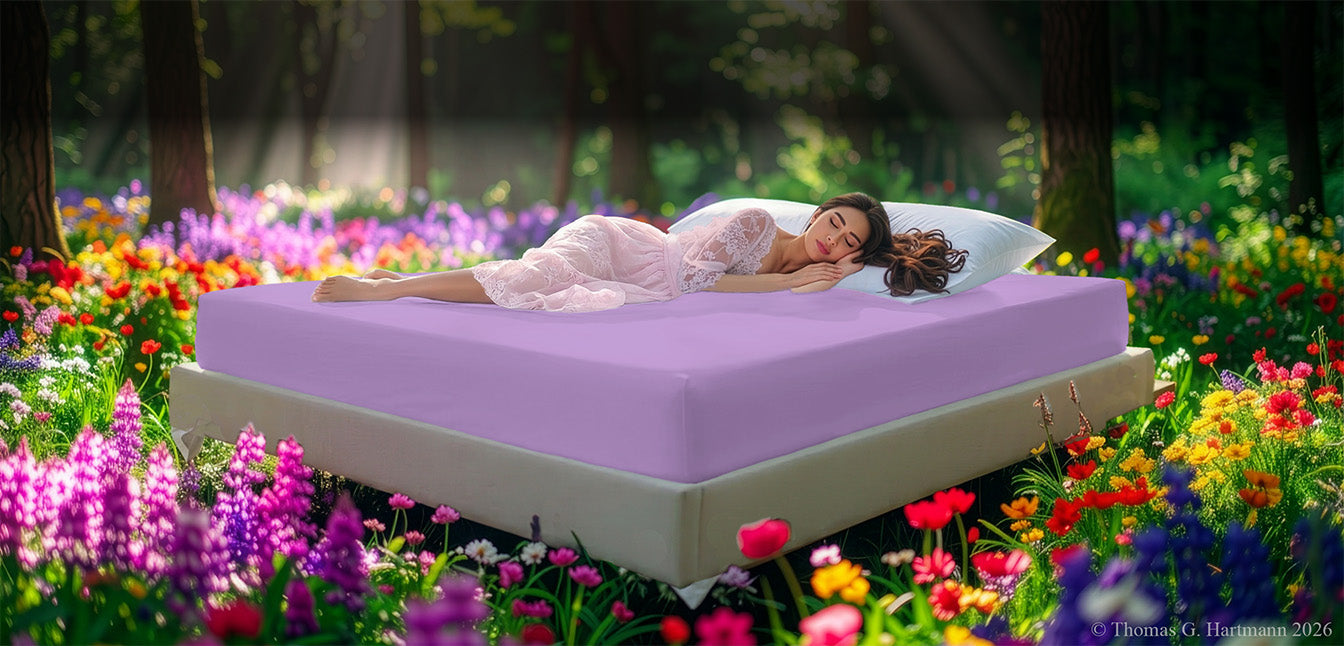 EGINO Lilac jersey stretch sheet on an outdoor bed surrounded by a blooming spring meadow, with a woman resting peacefully in soft morning light