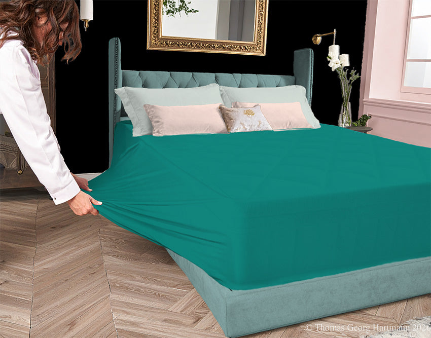 Evergreen jersey-knit stretch fitted sheet on an extra-deep mattress — pulling the sidewall over a foot outward to demonstrate the abundant stretch, making sheet changing effortless even for those with limited strength or mobility.